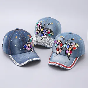Detailed view of denim baseball caps with colorful rhinestone butterfly patterns