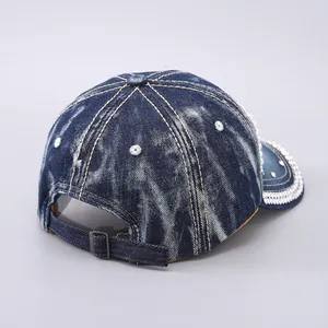 Detail view of the adjustable metal buckle and strap on the washed denim baseball cap