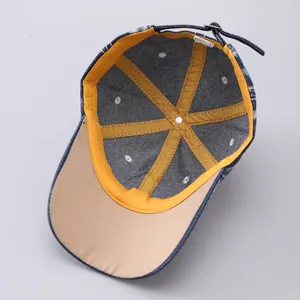 Detail of denim baseball cap interior showing yellow reinforced tape and metal buckle