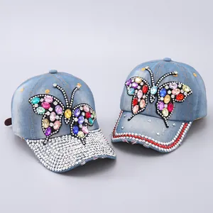Detailed view of denim baseball caps with colorful rhinestone butterfly and crystal brim