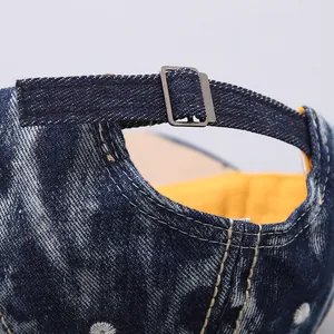 Detail of adjustable metal buckle and stitching on blue denim baseball cap