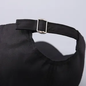 Macro detail of the adjustable silver metal buckle on the black twill baseball cap