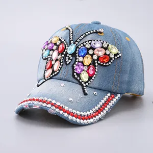 Close-up of denim baseball cap featuring colorful gemstone butterfly and silver studs