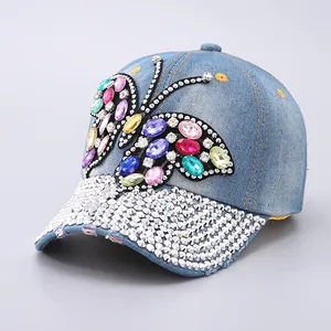 Detail of blue denim baseball cap featuring colorful rhinestone butterfly and crystal brim