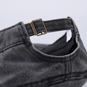 Detail of adjustable metal buckle and washed denim texture on a dark grey baseball cap