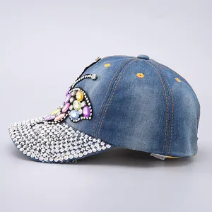 Close-up of sparkling rhinestone butterfly and crystals on blue denim baseball cap