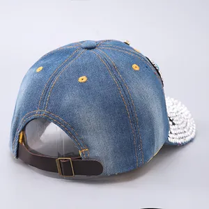 Detail of adjustable leather strap and bronze metal buckle on denim baseball cap