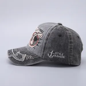 Detail of washed denim baseball cap with shark mouth embroidery and distressed brim