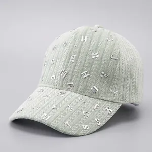 Detail of mint green corduroy baseball cap with scattered silver metal letter ornaments