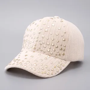 Detailed view of beige ribbed fabric baseball cap with gold stud embellishments
