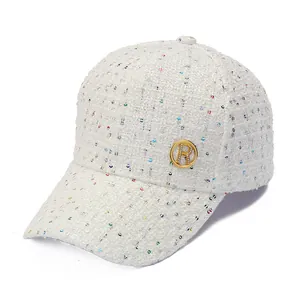 Detail van de witte tweed baseballpet met glinsterende pailletten en gouden R-logo