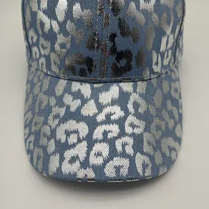 Detailed macro view of silver metallic leopard print on blue denim baseball cap texture