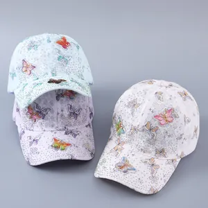 Detail of lace baseball caps with embroidered butterflies and rhinestones in soft colors