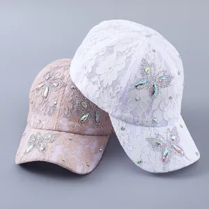 Detail von floralen Spitzen-Baseballkappen mit Strass-Schmetterlingsverzierungen in Weiß und Rosa