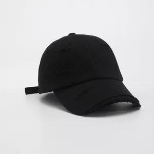 Detail view of black distressed vintage baseball cap with ripped fabric and frayed edges