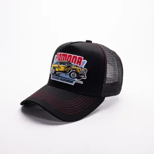 Dettaglio del ricamo vintage e cuciture rosse a contrasto sul cappello trucker nero