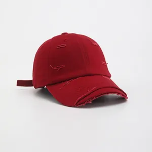 Detail of distressed dark red cotton canvas baseball cap with worn vintage effects