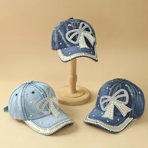 Close-up of denim baseball caps with rhinestone bows and pearls in three blue shades