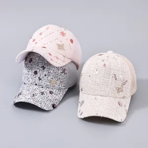 Dettaglio di berretti in tweed rosa e grigio con fiori di paillettes e retina