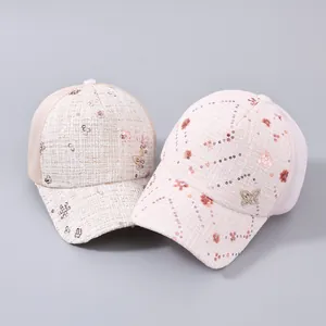 Dettaglio di cappellini in tweed con rete, fiori di paillettes e ciondolo a farfalla in metallo