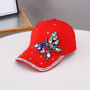 Détail de casquette en coton rouge avec papillon en strass colorés et double rangée de cristaux