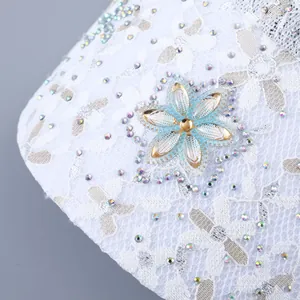 Makroaufnahme der weißen Spitzenkappe mit eleganten Strassblumen und Pailletten