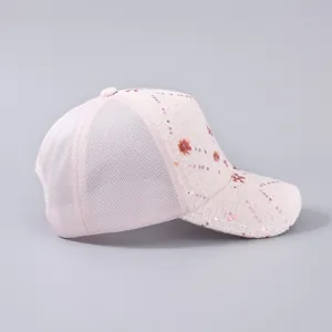 Dettaglio laterale di cappellino rosa con paillettes floreali e pannelli in rete mesh