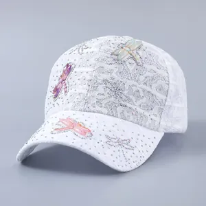 Close-up of white lace baseball cap with colorful 3D dragonfly patches and rhinestones