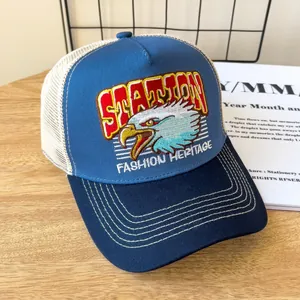 Dettaglio della toppa ricamata con aquila su un cappello trucker in rete blu e bianco