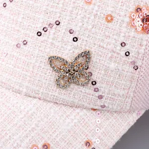 Dettaglio macro del cappello pied de poule con paillettes luccicanti e farfalla di strass