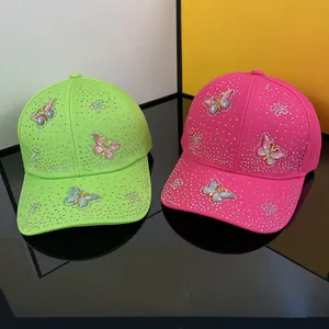 Detailed close-up of rhinestone baseball caps featuring 3D butterfly embroidery in neon pink