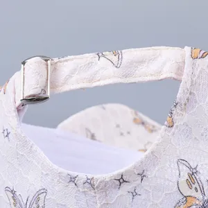 Close-up of white lace baseball cap featuring silver metal adjustable buckle and butterfly print