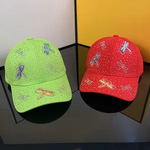 Neon green and bright red baseball caps with rhinestone dragonfly patterns and crystal accents