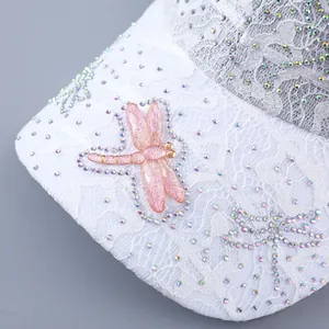 Detail view of pink dragonfly ornament and rhinestones on white lace baseball cap