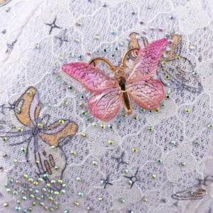 Macro detail of white lace cap with 3D gradient butterflies and sparkling rhinestones