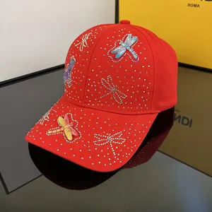 Detailed close-up of rhinestone dragonfly patterns on a premium red baseball cap