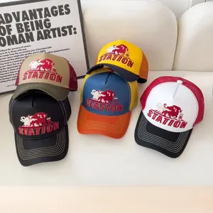 Dettaglio di cappellini trucker con ricamo STATION bull su un divano chiaro