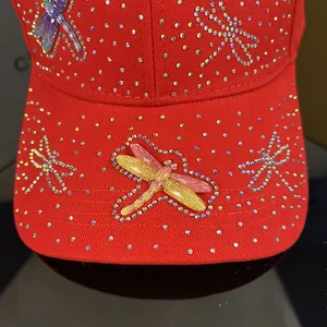 Detail of dragonfly embroidery and rhinestones on a deep red cotton baseball cap