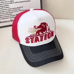 Dettaglio del logo del toro ricamato e testo STATION su cappello trucker rosso e bianco