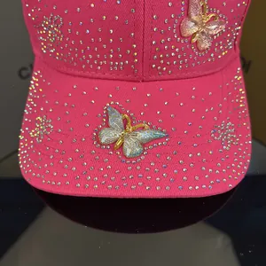 Close-up of pink baseball cap with crystal rhinestones and golden butterfly accents