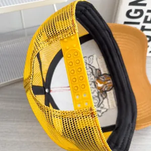 Dettaglio della chiusura snapback e della rete sul cappellino trucker giallo e marrone