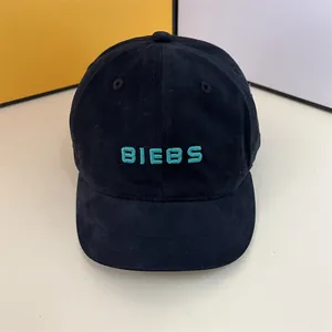 Detailed view of the green embroidered BIEBS lettering on a black cotton baseball cap