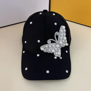 Detailed view of black baseball cap with elegant faux pearls and rhinestone butterfly design