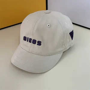 Close-up of beige short brim baseball cap with purple embroidered BIEBS lettering detail