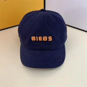 Detailed embroidery of orange BIEBS letters on a navy blue cotton baseball cap