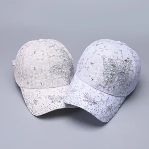 Close-up of the delicate floral lace texture and shiny rhinestone butterfly on baseball caps