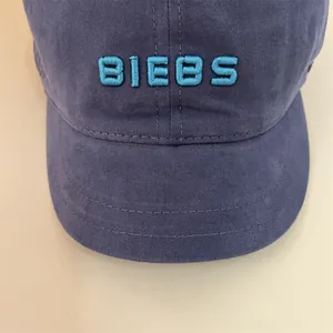 Close-up of light blue 3D BIEBS embroidery on a vintage washed navy cotton baseball cap