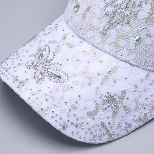 Close-up of intricate lace fabric and sparkling rhinestone details on the baseball cap brim