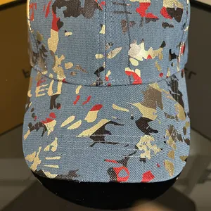 Detailed close-up of blue camo baseball cap showing thick fabric texture and gold splashes