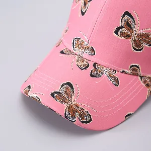 Close-up detail of pink baseball cap showing intricate butterfly prints and precise stitching